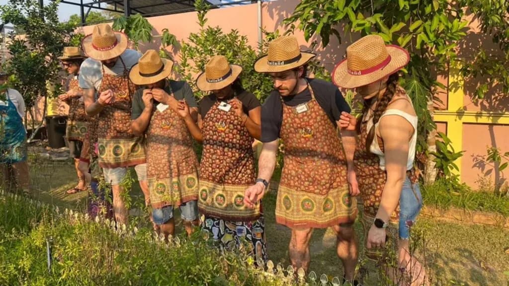 Tourists at Siam Garden Cooking School in Chiang Mai, exploring the herb garden as part of their Chiang Mai excursion.