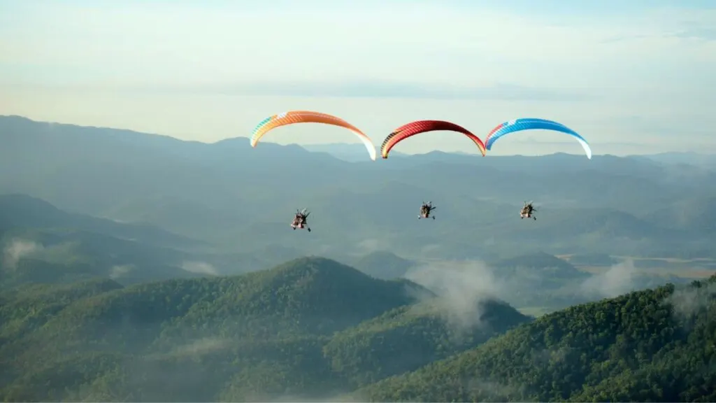 Group paramotoring over misty mountains on a Chiangmai Go Tours trip