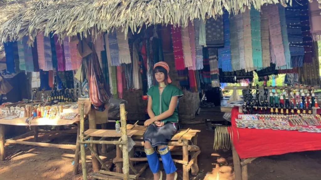 Local woman from long-neck tribe selling artisan crafts during Chiang Rai excursion