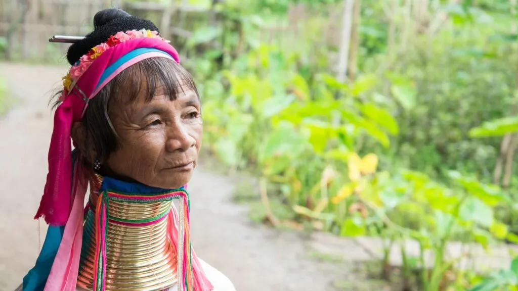 A Long Neck woman in traditional attire with brass rings around her neck, showcasing the unique cultural heritage of the Karen tribe in a village near Chiang Rai