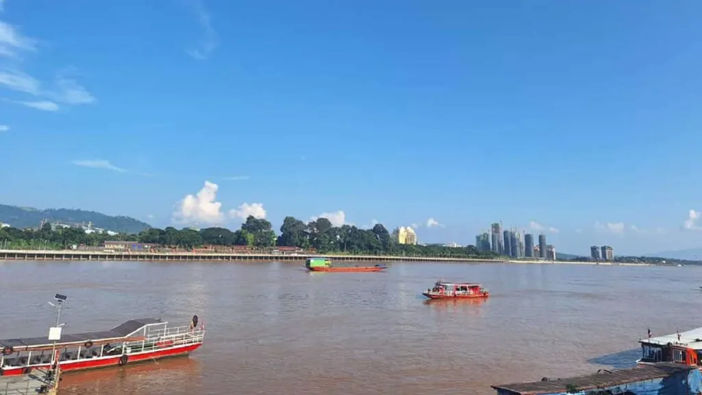 A panoramic view of the Mae Khong River at the Golden Triangle, where the borders of Thailand, Laos, and Myanmar meet, with boats cruising along the water.