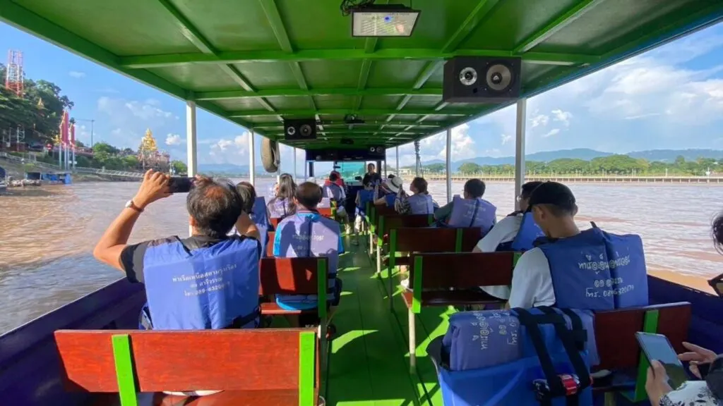 Tourists enjoying a boat ride with a view of the Golden Buddha on a Chiang Mai to Chiang Rai tour - Perfect for scenic and cultural experiences.