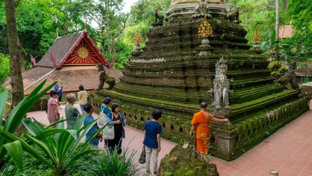 Tourist capturing the intricate details of Wat Umong Chedi during a Chiang Mai tour, emphasizing the site’s cultural significance and natural beauty