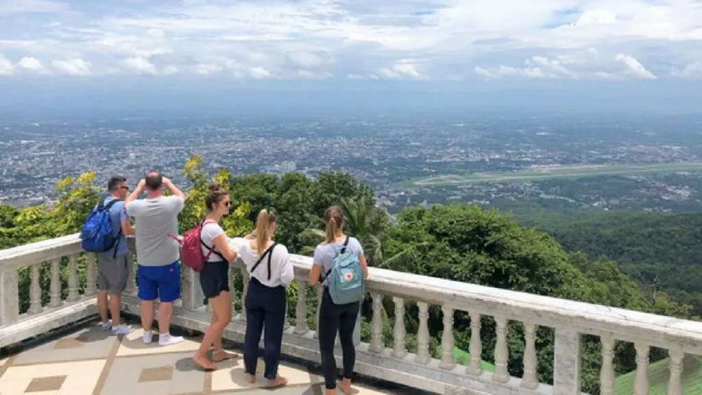 Tourists enjoying a scenic view from Doi Suthep during a Chiang Mai tour, surrounded by lush mountains and clear blue skies