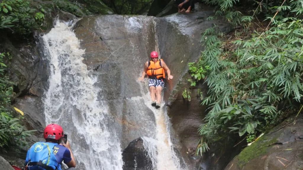 Traveler enjoying a waterfall slide adventure as part of a Chiang Mai excursion
