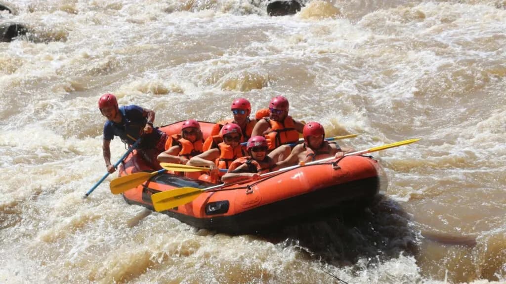 Adventurous group of travelers and guide facing thrilling white water on a Chiang Mai excursion