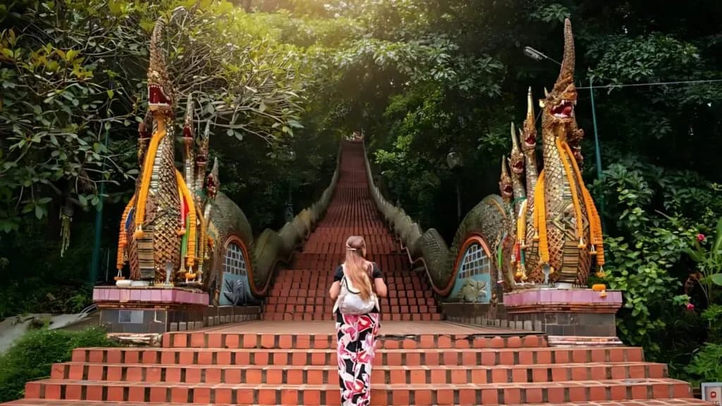 Visitor ascending the grand staircase at Wat Phra That Doi Suthep, a must-see temple on a Chiang Mai tour, known for its stunning architecture and spiritual ambiance. Perfect for Chiang Mai excursions and cultural exploration.