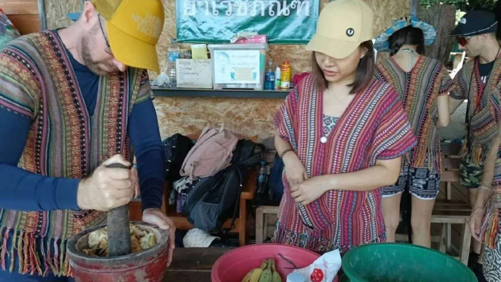 A visitor learns to make elephant food with a staff member on a Chiang Mai tour.