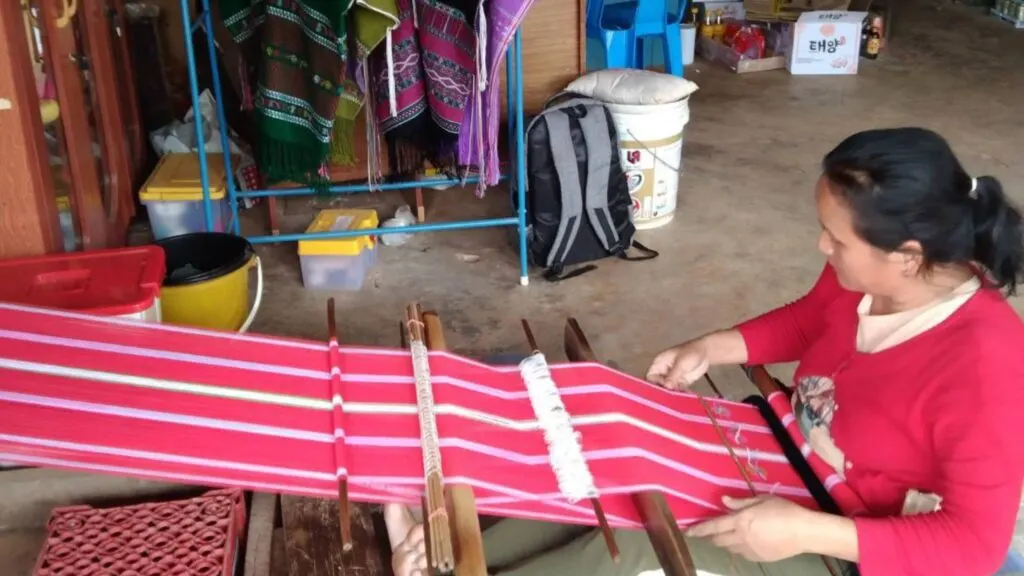 Karen woman weaving fabric by hand in her village, showcasing local culture during Doi Inthanon Chiangmai excursion