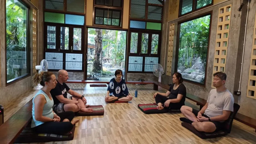 Group meditation session inside a tranquil yoga hall during a Chiang Mai wellness excursion.