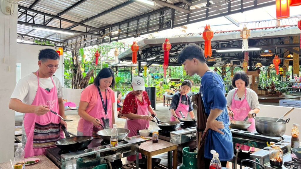 Group of travelers in a Thai cooking class, a popular activity on Chiang Mai tours, learning to cook traditional recipes.
