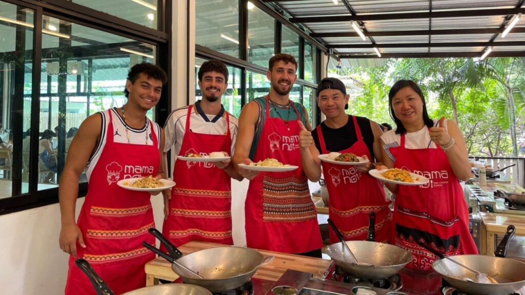 Group of happy tourists displaying their homemade Thai dishes after a cooking class during a Chiang Mai tour.