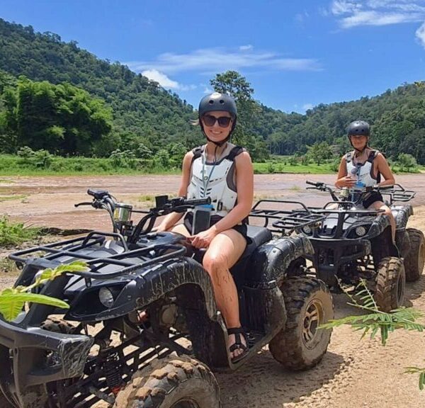 Two tourists enjoying an exhilarating ATV ride through the scenic landscapes of Chiang Mai during an adventurous Chiang Mai tour