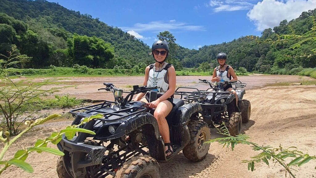 Two tourists enjoying an exhilarating ATV ride through the scenic landscapes of Chiang Mai during an adventurous Chiang Mai tour