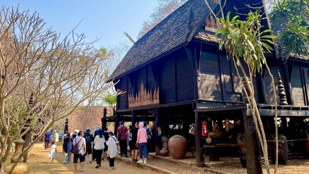 Visitors exploring the Black Museum, with its intricate wooden structures and eclectic art collections created by the renowned Thai artist Thawan Duchanee