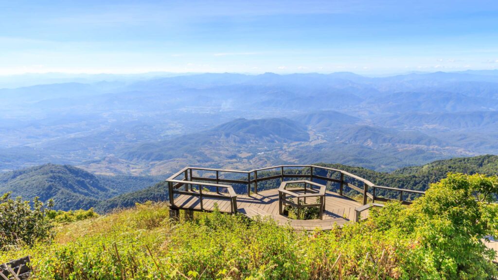 View from Kew Mae Paan Bridge during a Chiang Mai tour, showcasing lush green valleys and distant mountains under a clear blue sky