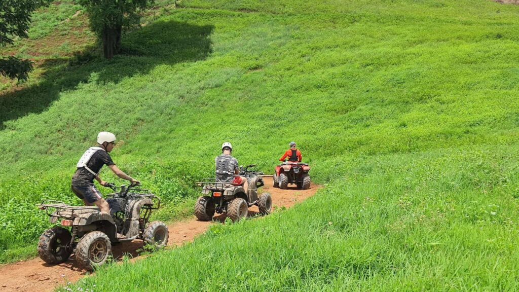 Group of tourists riding ATVs along a stunning green hill, experiencing the thrill of Chiang Mai excursions in the great outdoors