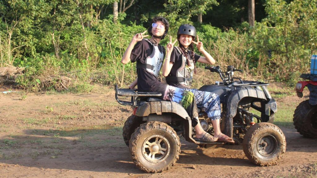 Two tourists riding an ATV, enjoying the adventure and scenic beauty during their Chiang Mai tour in the lush countryside