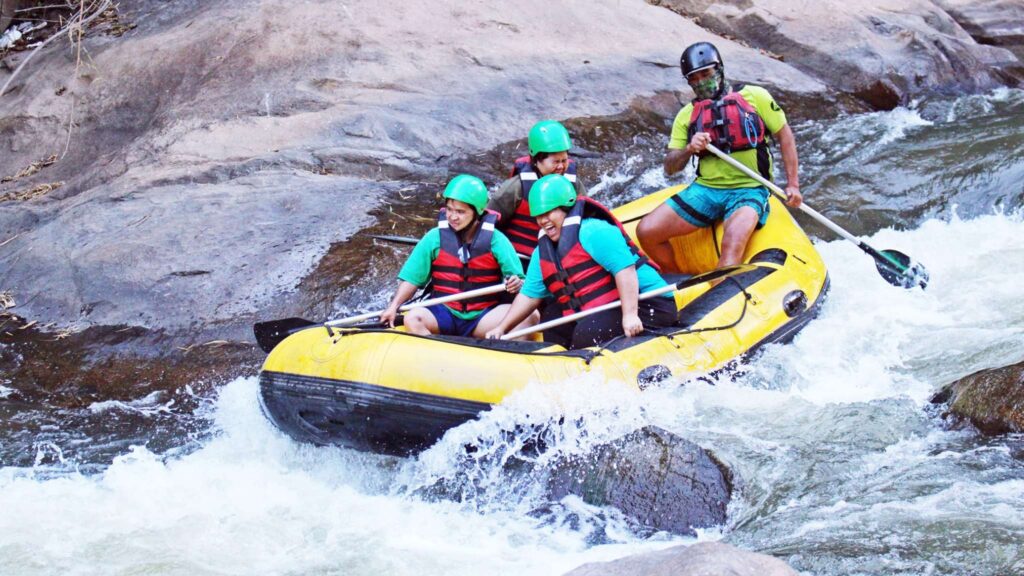 Group of excited and slightly scared travelers navigating rapids while rafting, capturing the thrill of Chiang Mai excursions on the water