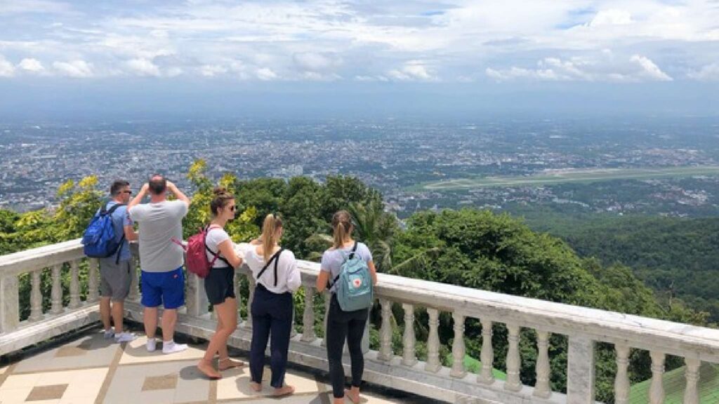 Tourists enjoying a scenic view from Doi Suthep during a Chiang Mai tour, surrounded by lush mountains and clear blue skies