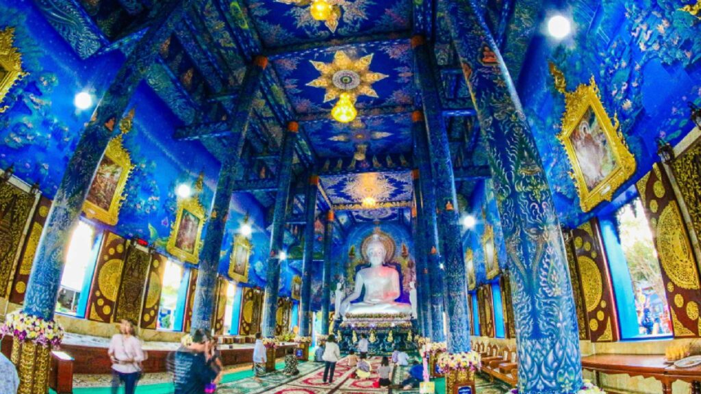 Tourists admiring the majestic Blue Temple, known for its deep blue color and striking golden accents, a blend of traditional and modern artistry in Chiang Rai