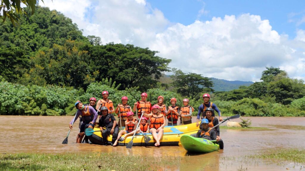 Happy group of travelers and tour guide posing after a thrilling Chiang Mai white water rafting tour