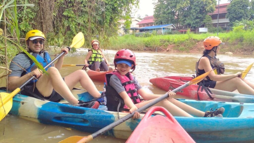 Family kayaking on Mae Ping River during a Chiang Mai tour, enjoying the scenic views and nature