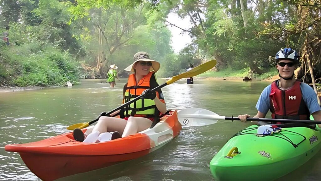 Tourists kayaking along a scenic river in Chiang Dao, surrounded by lush greenery.
