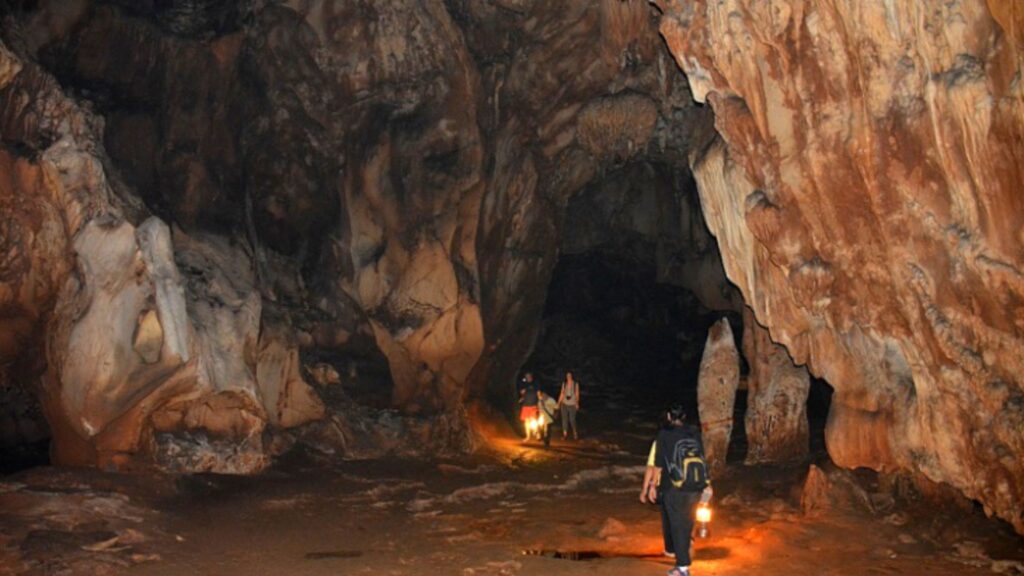 Traveler exploring the Chiang Dao Cave with a local guide, a thrilling part of this Chiang Mai adventure tour.