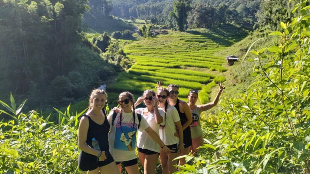 Group of tourists taking a photo during a day trip trekking in Chiang Mai with stunning views of rice fields behind them
