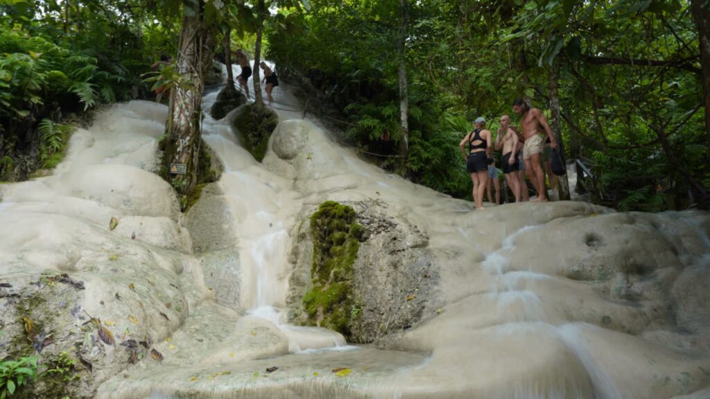 Tourists walking up the natural Sticky Waterfall in Chiang Mai jungle tour
