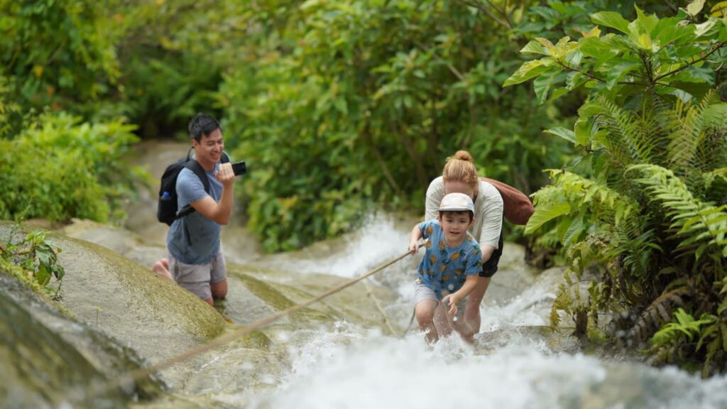 Parent and kid are walking up using the rope for sticky waterfall in chiangmai