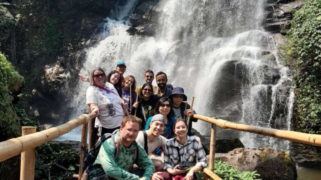 Tourists posing for a picture on a Chiang Mai tour, with waterfall in the background