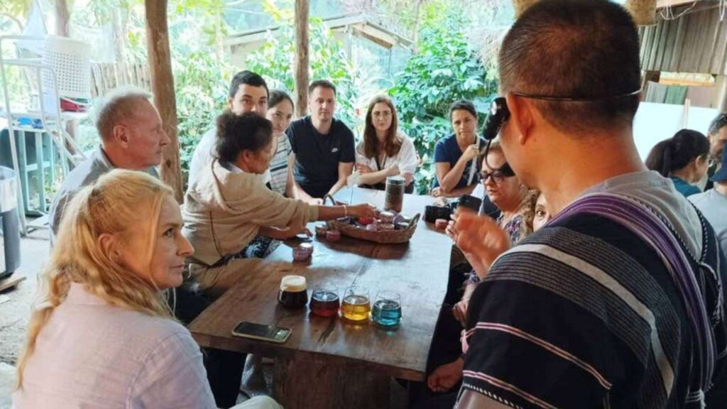 Tourist enjoying traditional Thai coffee at a Karen village during a Chiang Mai tour excursion
