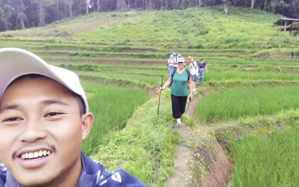 Guide and traveler trekking through the scenic rice fields in Chiang Mai, experiencing the beauty of rural landscapes