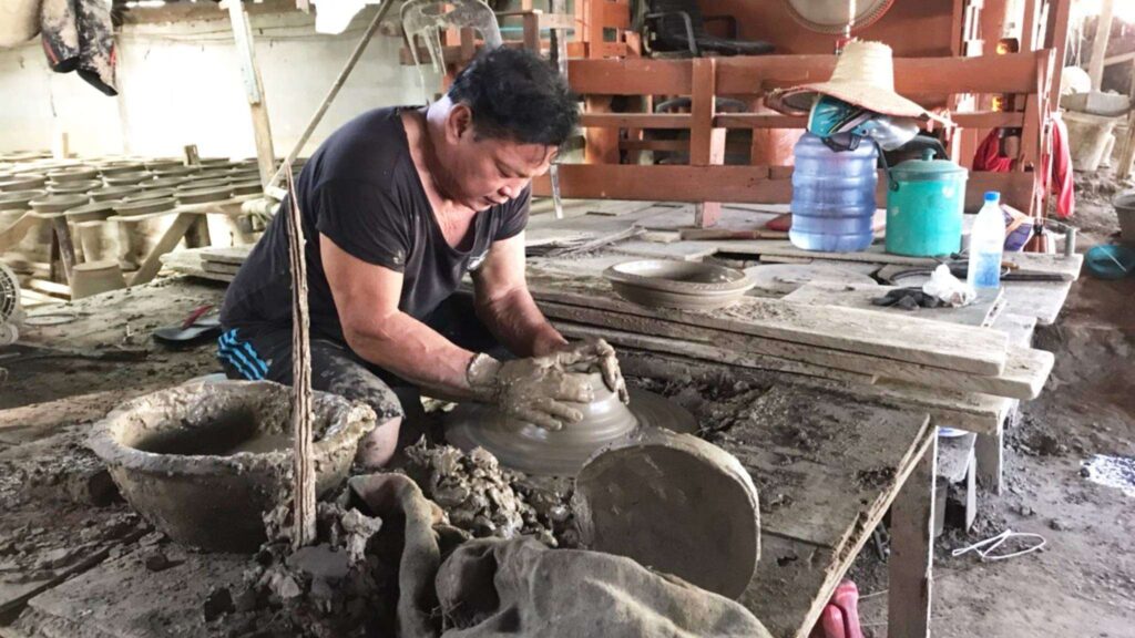 A local artisan crafting pottery at a workshop during a Chiang Mai tour, part of a cultural cycling excursion.