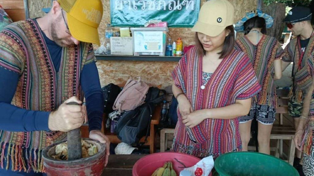 A visitor learns to make elephant food with a staff member on a Chiang Mai tour.