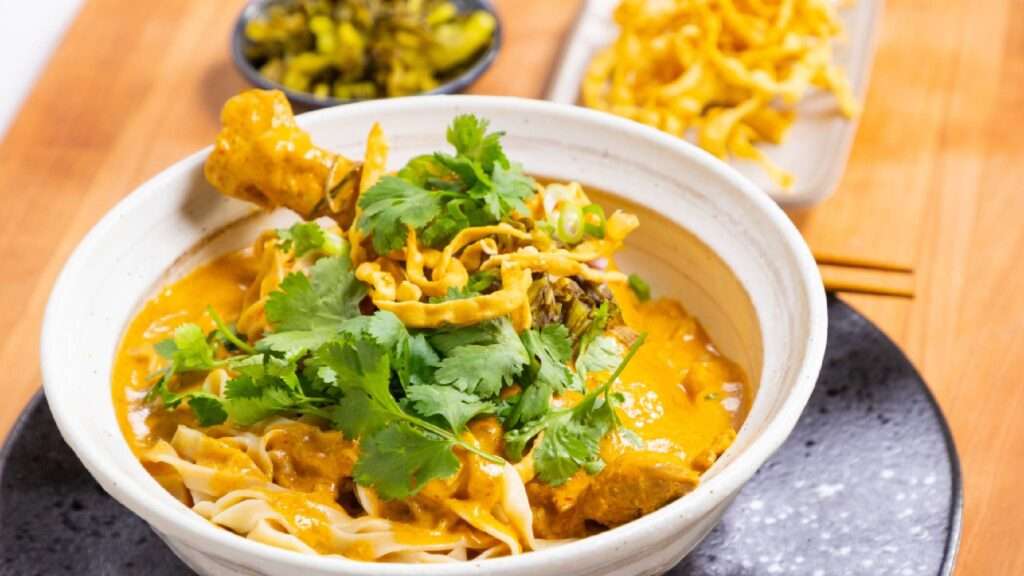Delicious bowl of Khao Soi, a must-try Northern Thai curry noodle dish, served with crispy noodles and fresh herbs. A top choice for food lovers exploring things to do in chiang mai.
