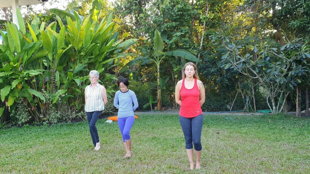 Guests practicing mindful walking meditation during a Chiang Mai yoga retreat surrounded by lush tropical gardens.